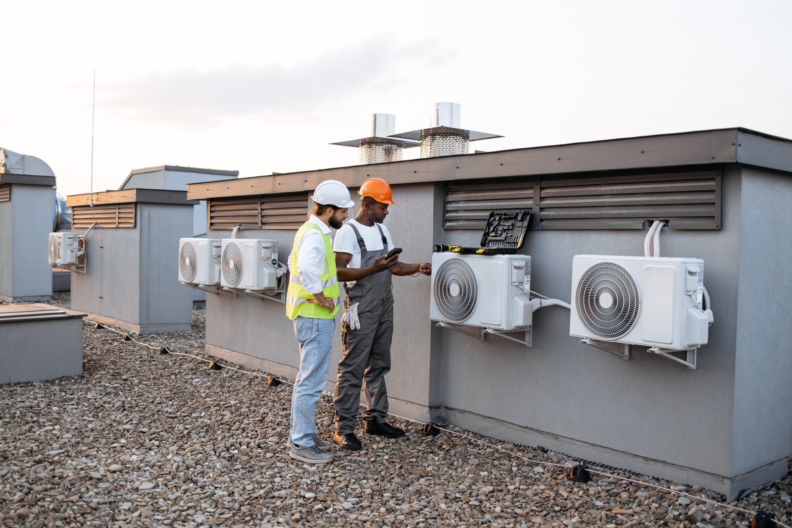 Two construction workers on roof inspecting cooling system